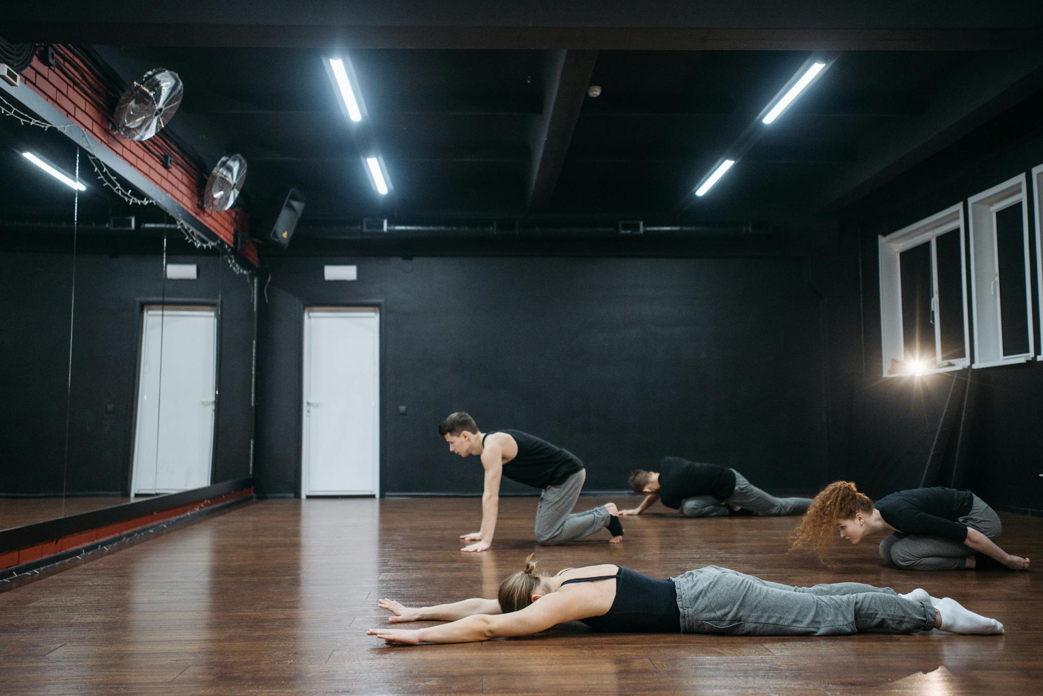 A diverse group of adults practicing stretching exercises in a dance studio.